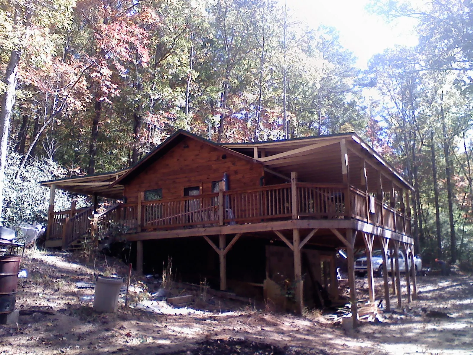 Log cabin with a wraparound porch and metal roof in the fall in Story City
