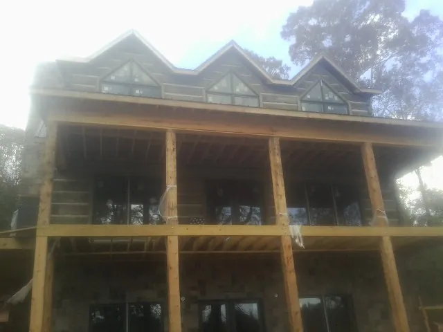 Dormers and porch framing on a large log home under construction — Roof Coating work by our crew in Story City