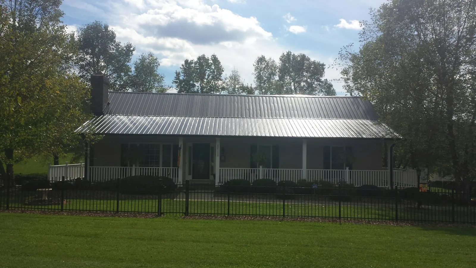 Gray metal roof on a brick ranch with a full width front porch — Gutter Guard Installation work by our crew in Story City