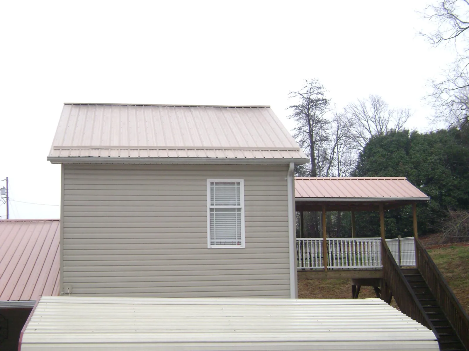 Tan metal roofs on a two story addition and attached porch, from a Roof Replacement job in Story City
