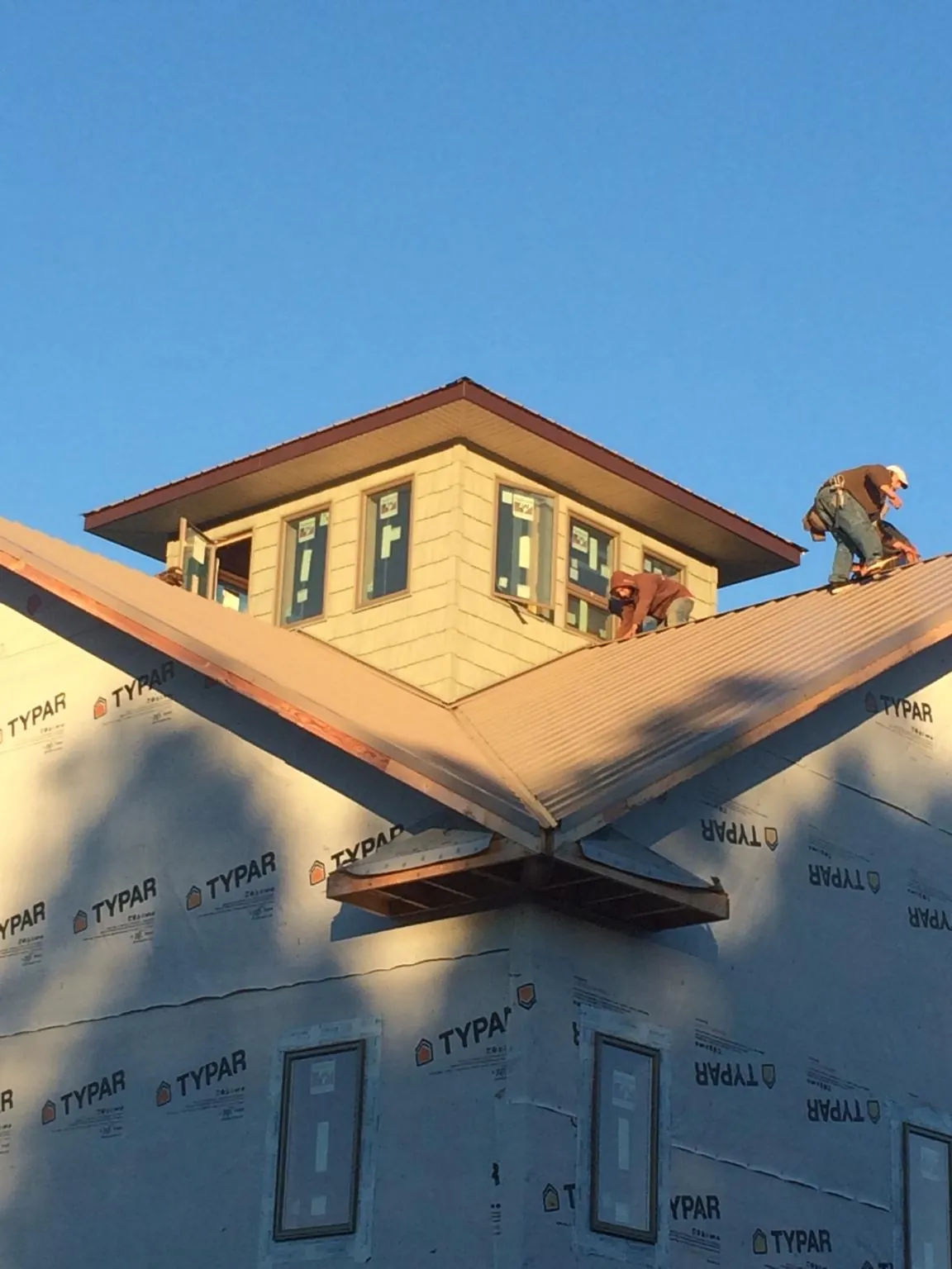 Roofers working around a rooftop cupola on a new metal roof at sunset — Roof Waterproofing in Story City by Roofing Brothers